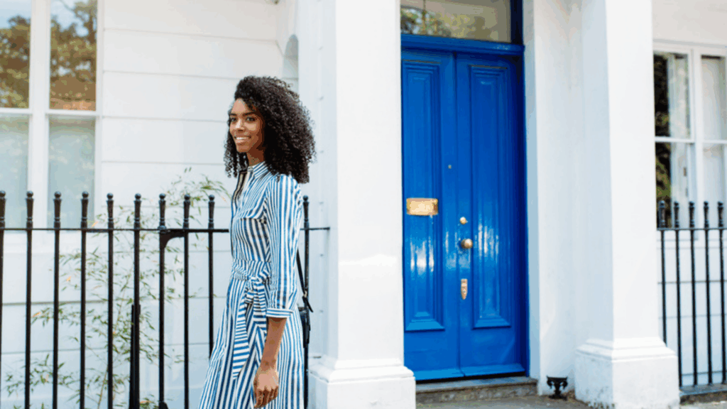 woman walking outside near a fence and house