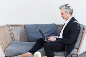 man sitting on couch typing on his laptop