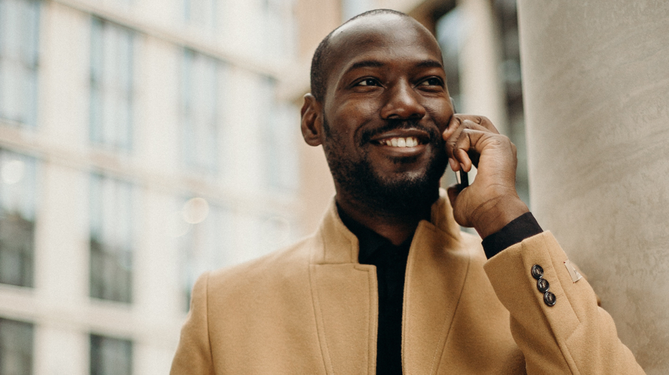man smiling while talking on cell phone