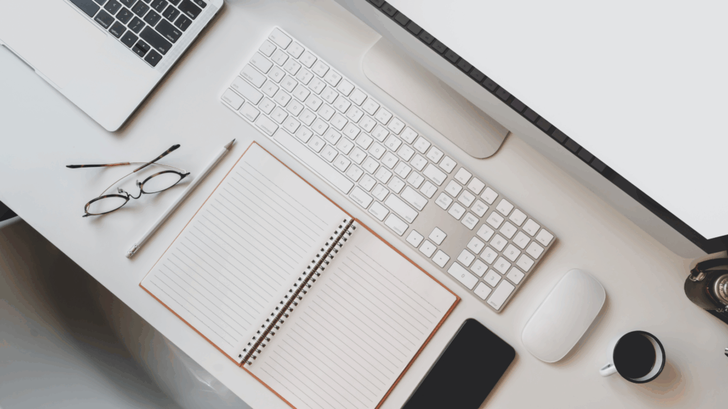 work desk with notebook, keyboard, and phone
